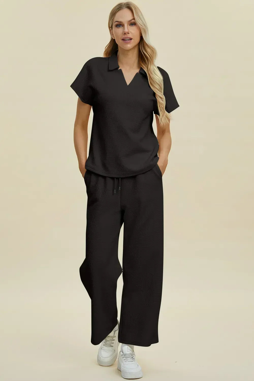 Woman wearing black relaxed-fit top and wide-leg pants set with short sleeves and white sneakers