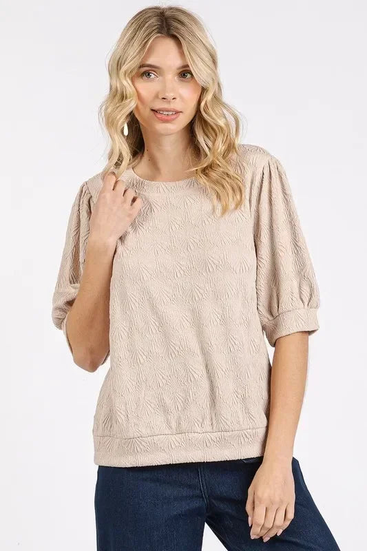 Woman wearing textured beige blouse with half sleeves and relaxed fit, styled with dark jeans