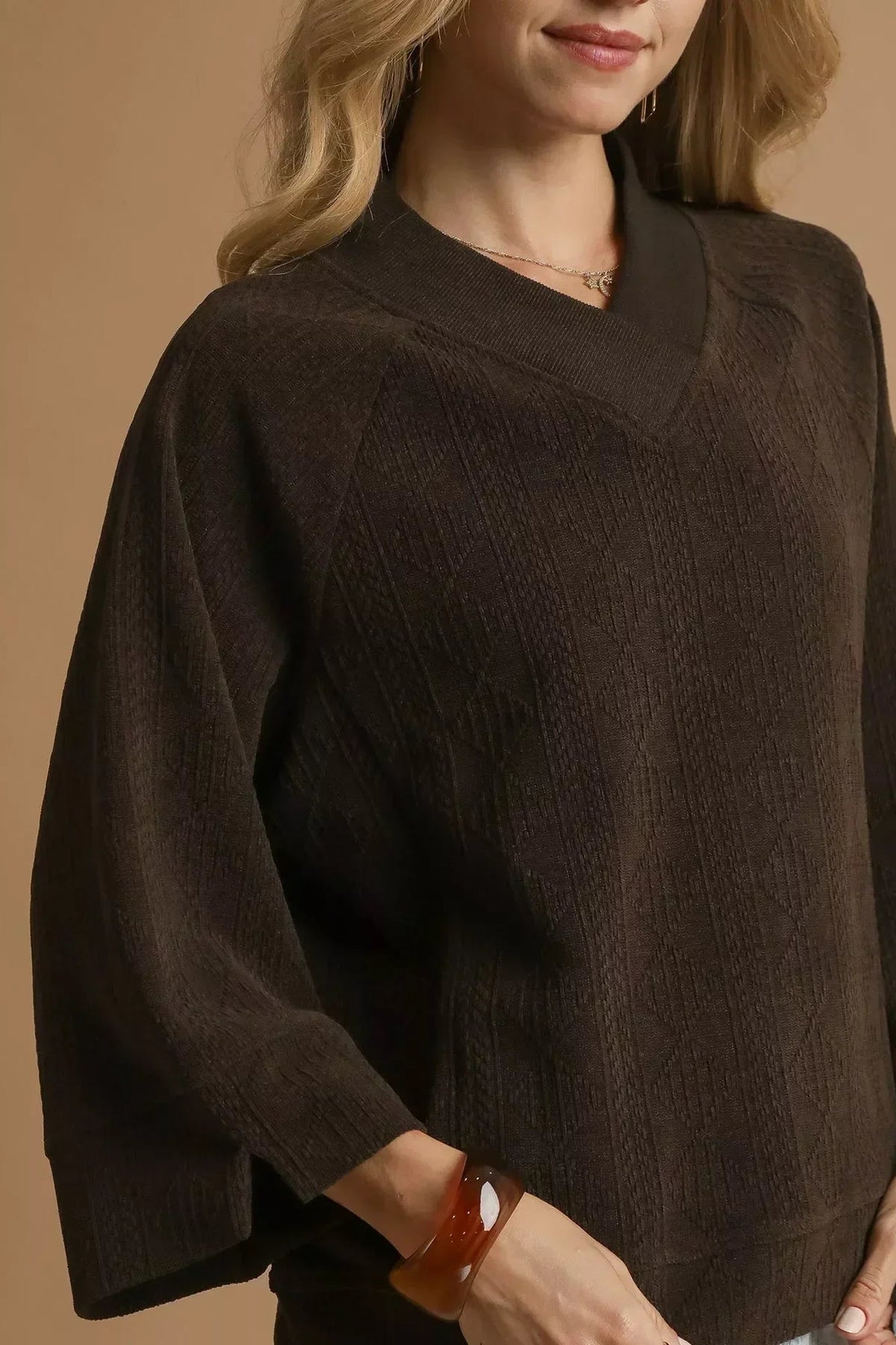 Woman wearing a chocolate brown textured knit sweater with loose sleeves