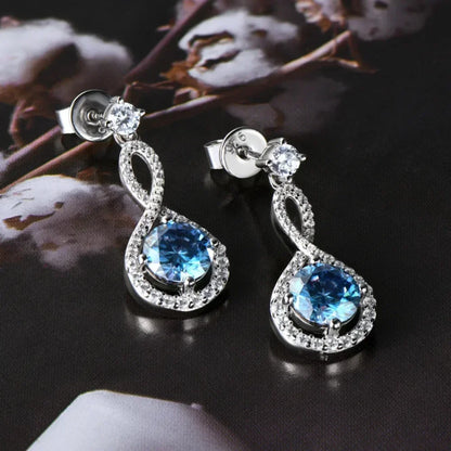 Silver drop earrings with blue gemstones and infinity loop design, displayed on dark surface.