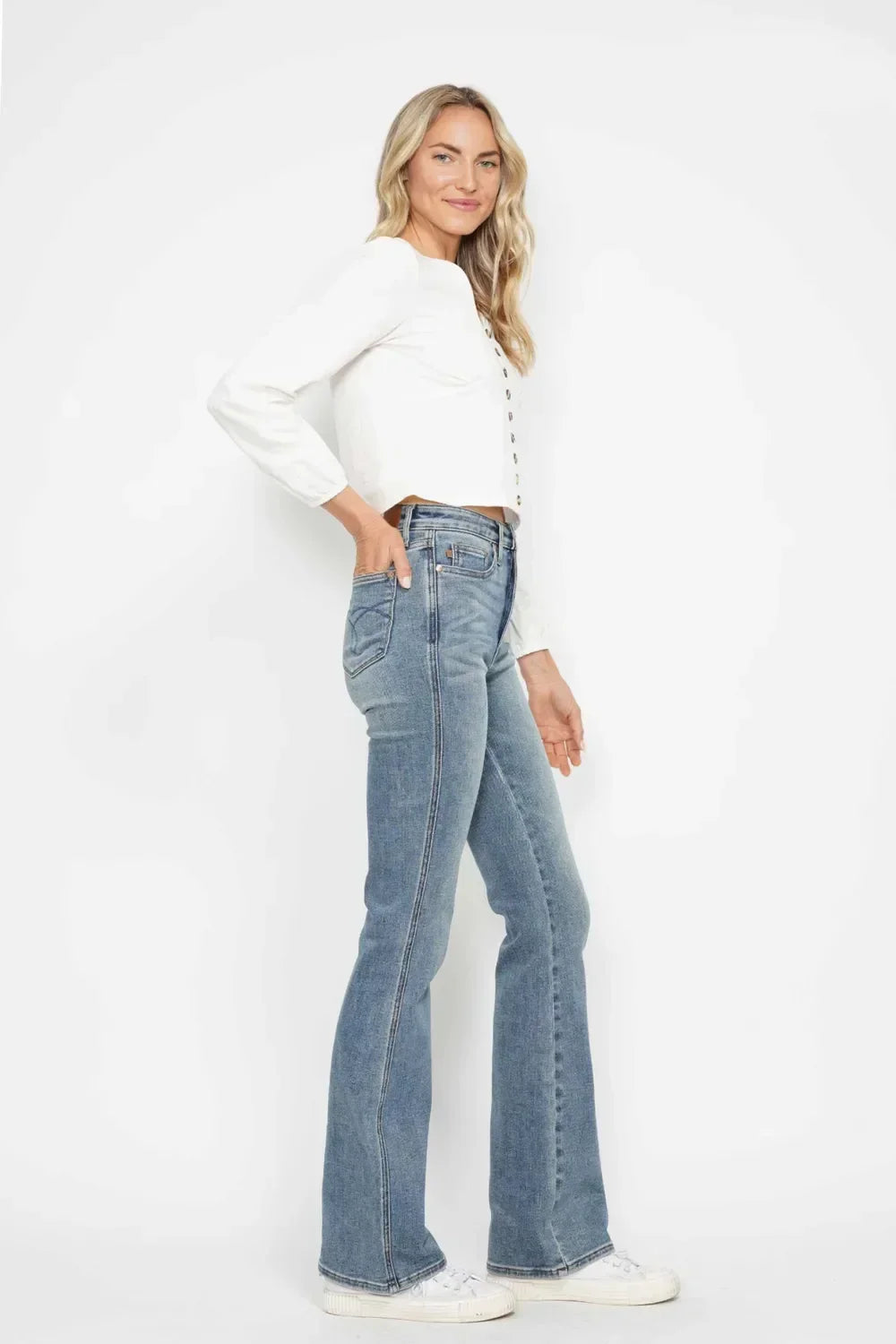 Woman in white button blouse and high-waisted flared jeans with white sneakers