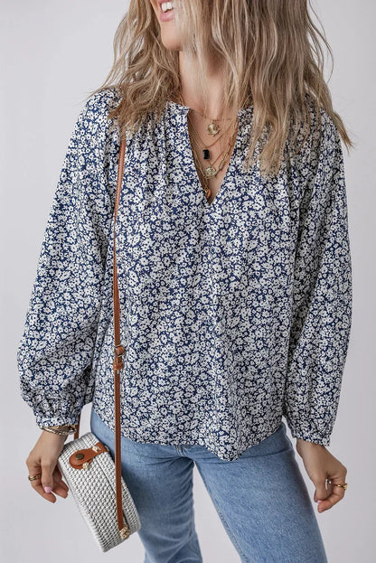 Woman wearing a blue floral blouse with balloon sleeves, light jeans, and woven crossbody bag