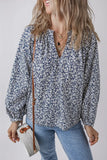 Woman wearing a blue floral blouse with balloon sleeves, light jeans, and woven crossbody bag