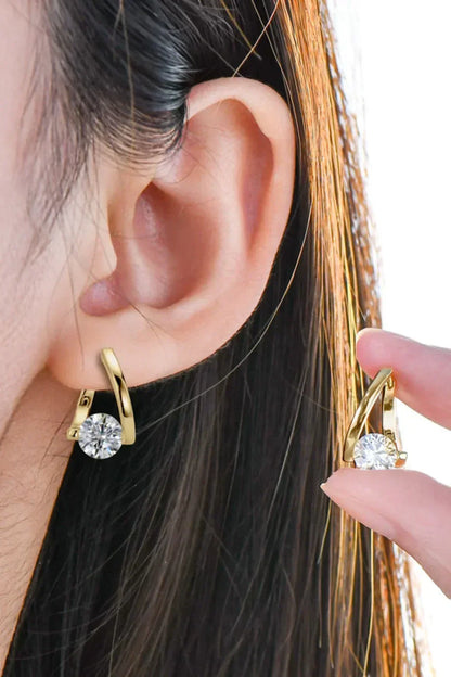 Woman wearing gold hoop earrings with round clear gemstone, close-up view