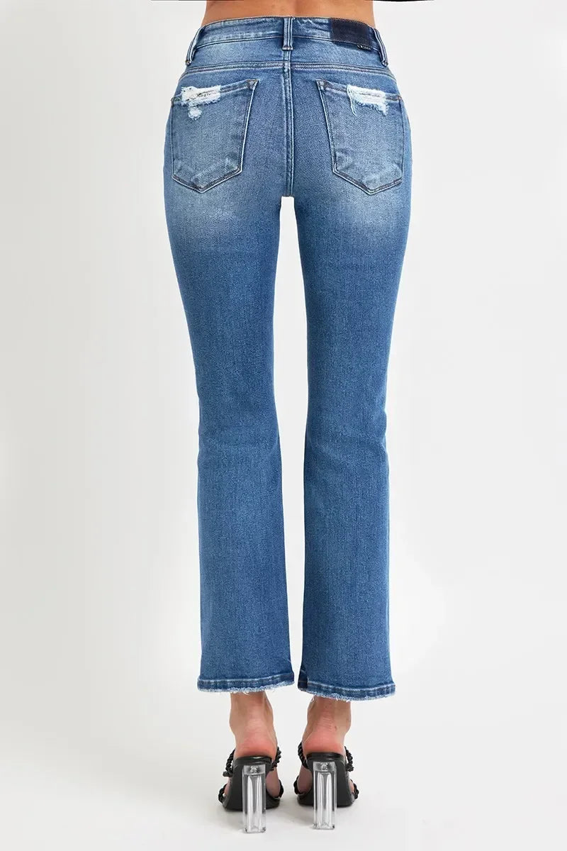 Back view of woman in distressed blue flare jeans and black heeled sandals