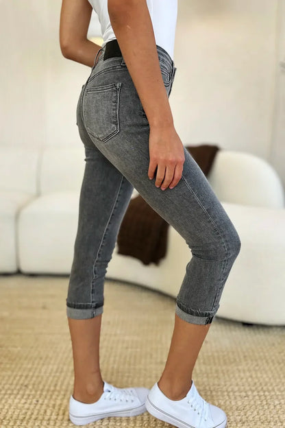 Woman wearing grey cropped skinny jeans with rolled cuffs and white sneakers indoors