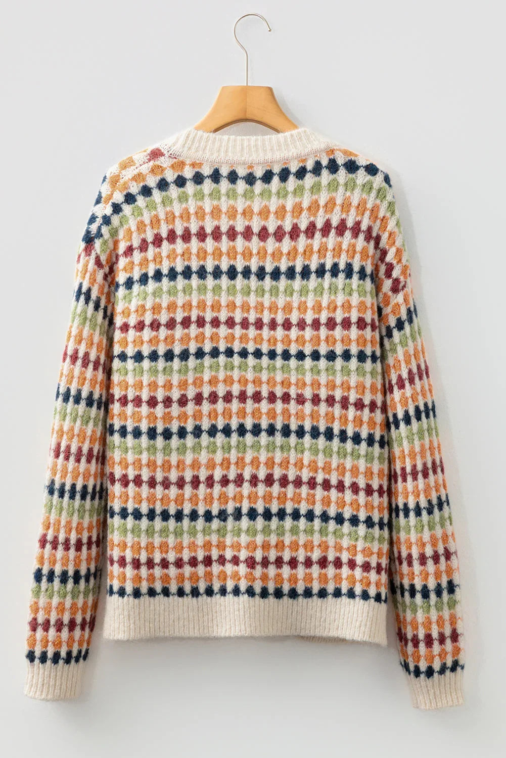 Back view of a multicolor patterned knit sweater with ribbed collar and cuffs, hanging on a wooden hanger.