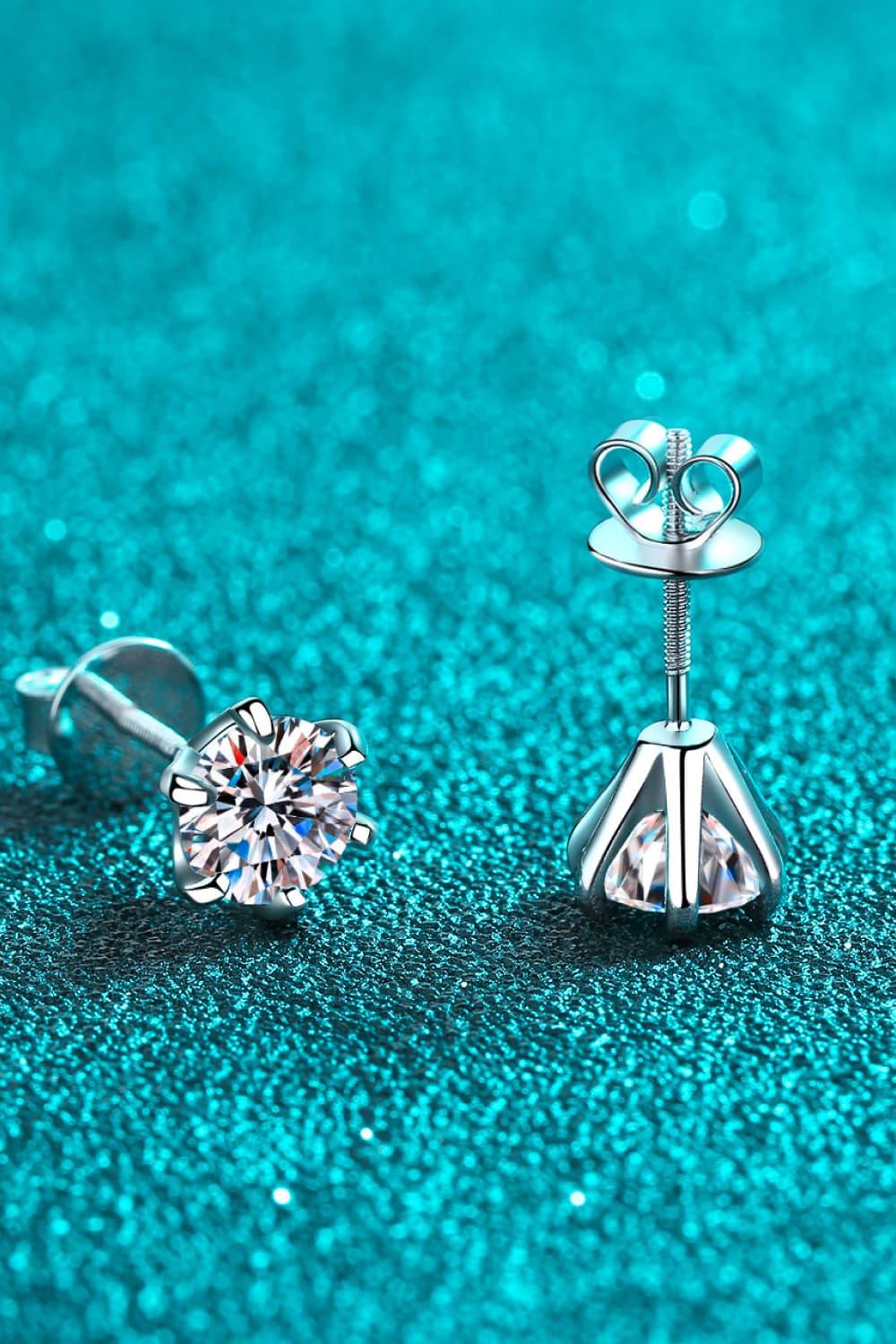 Silver stud earrings with clear round gemstones on a teal glitter background