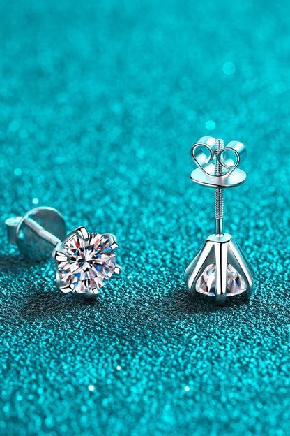Silver stud earrings with clear round gemstones on a teal glitter background