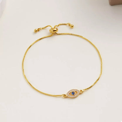 Gold adjustable bracelet with evil eye charm and blue center stone on neutral background