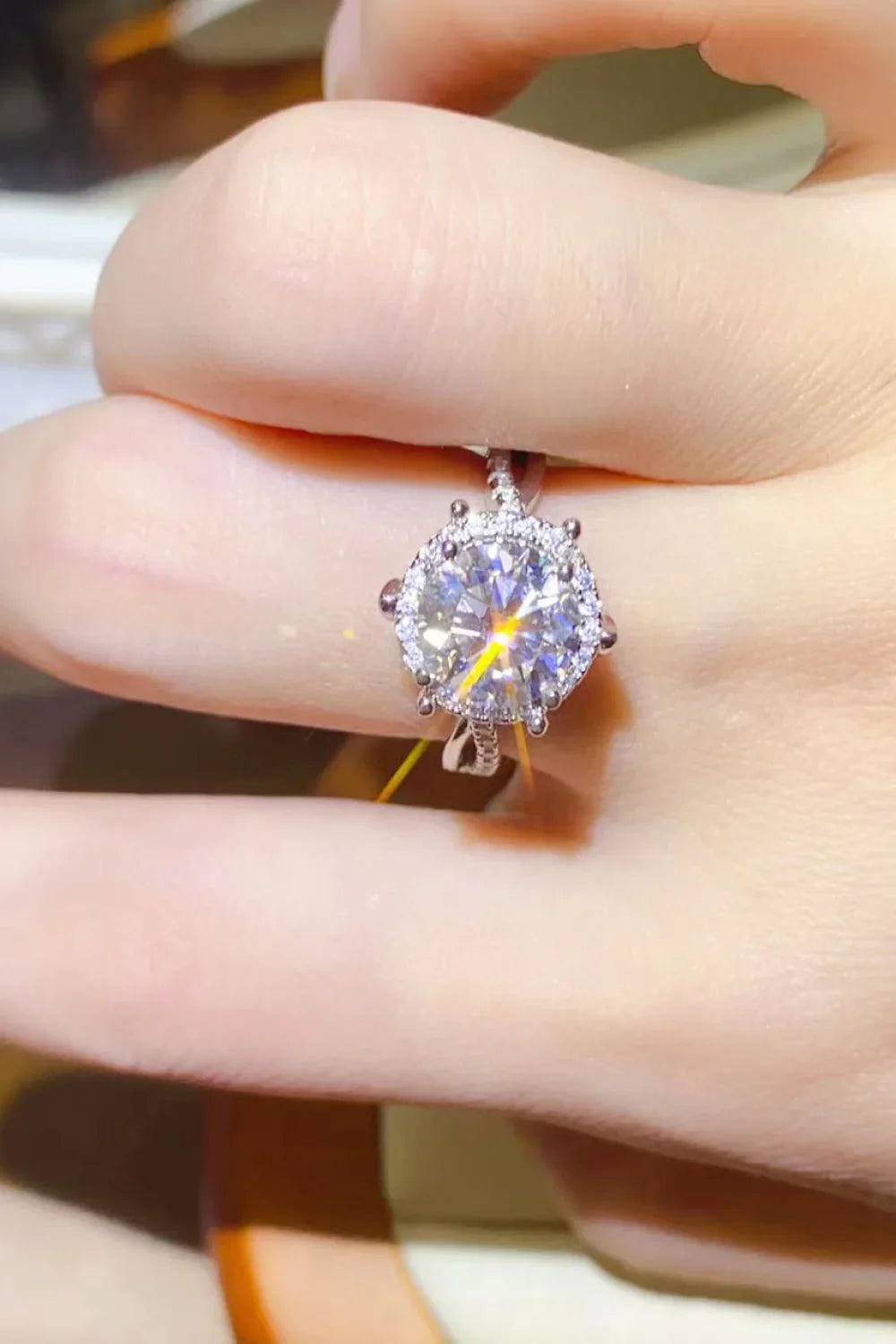 Hand wearing a round cut solitaire diamond ring with a pavé band, shown in close-up.