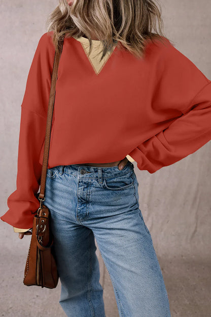 Woman wearing loose red long sleeve top, light wash jeans, and crossbody bag