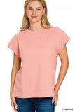 Woman wearing a textured pink short-sleeve top with relaxed fit and blue jeans