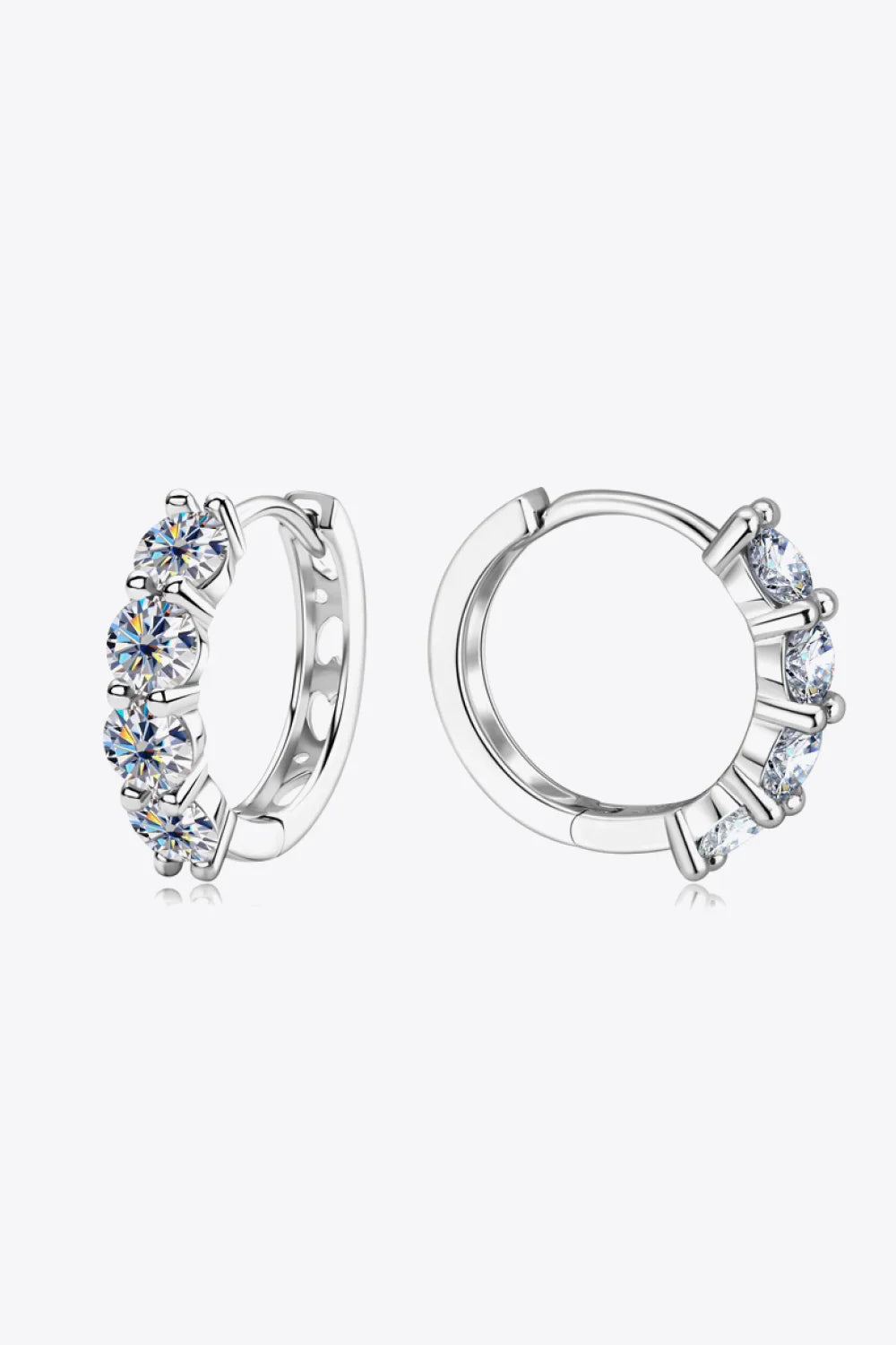 Silver hoop earrings with three round clear gemstones on a white background