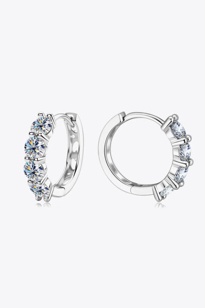 Silver hoop earrings with three round clear gemstones on a white background