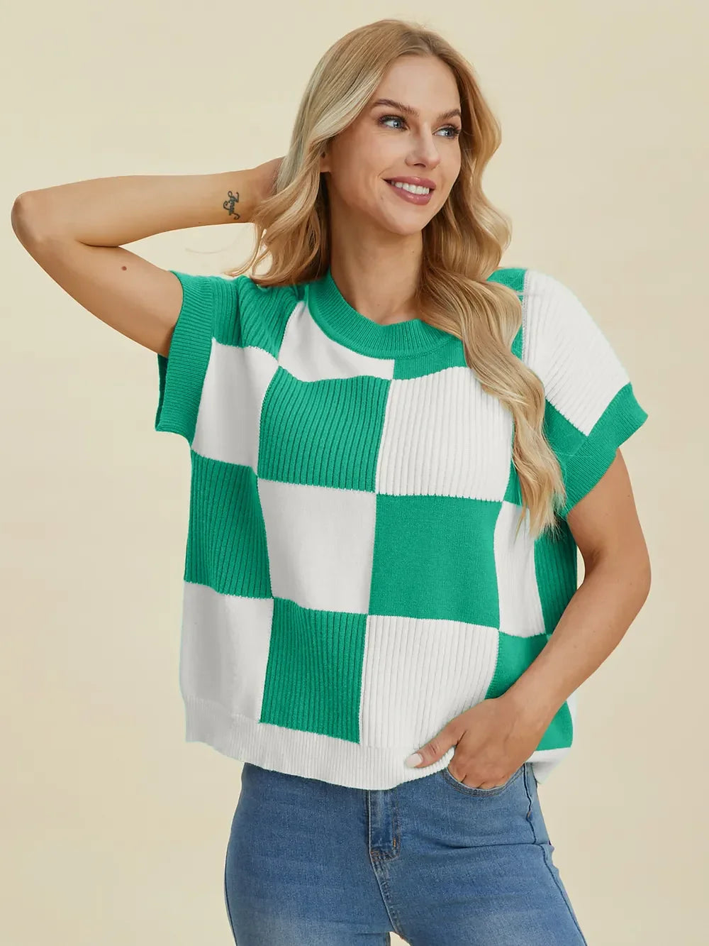 Woman wearing a green and white checkered short sleeve knit sweater with blue jeans