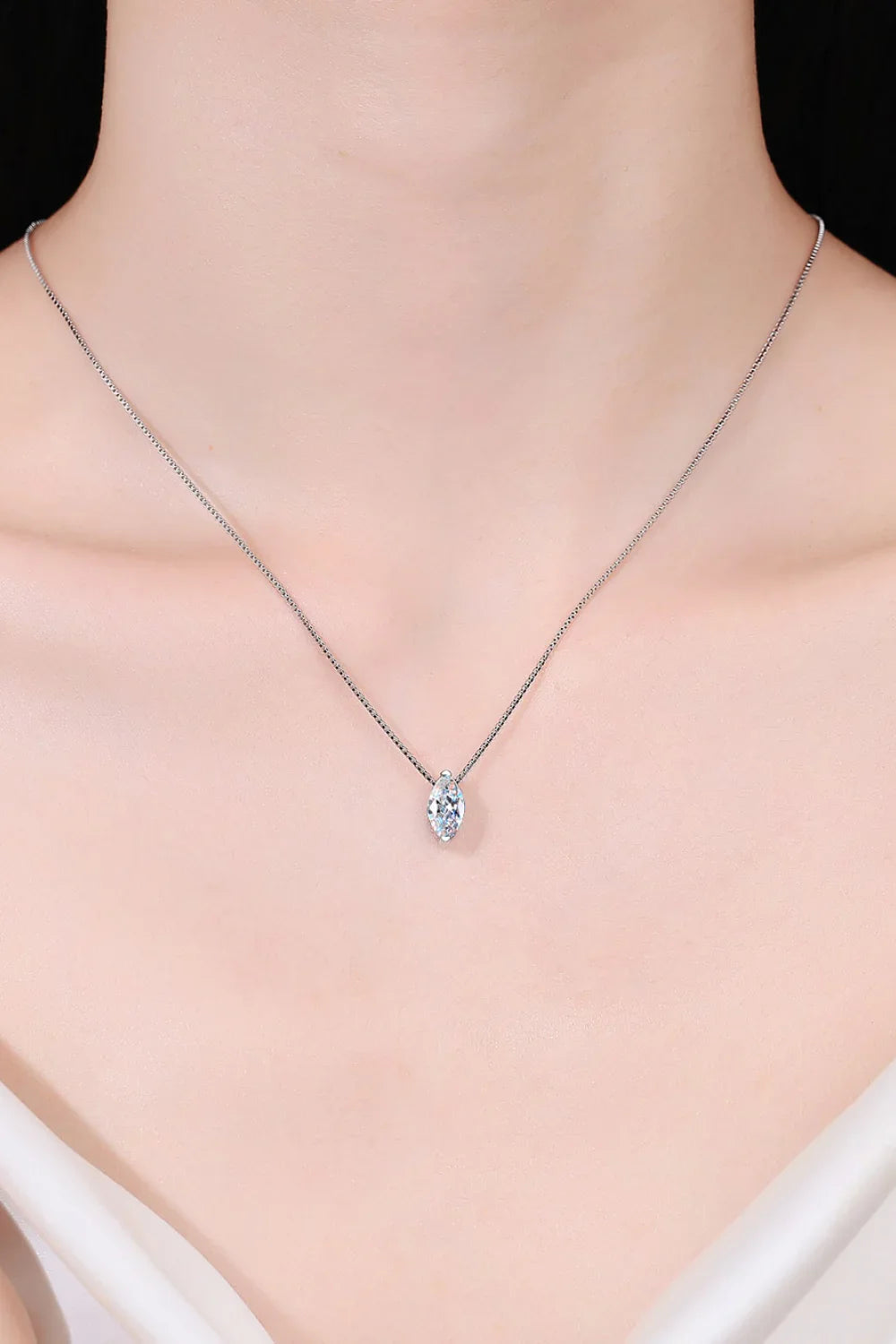 Delicate silver chain necklace with marquise-cut crystal pendant on model's neck