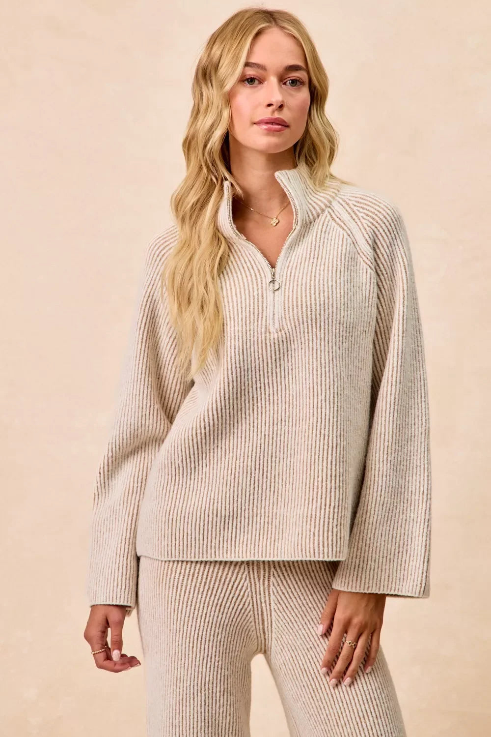 Woman wearing a beige ribbed knit half-zip pullover and matching pants, relaxed fit.
