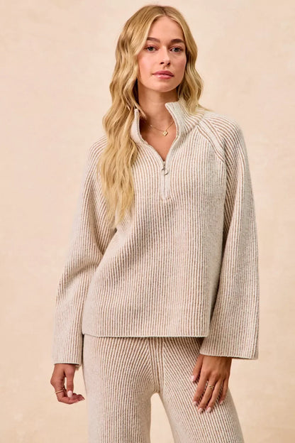 Woman wearing a beige ribbed knit half-zip pullover and matching pants, relaxed fit.