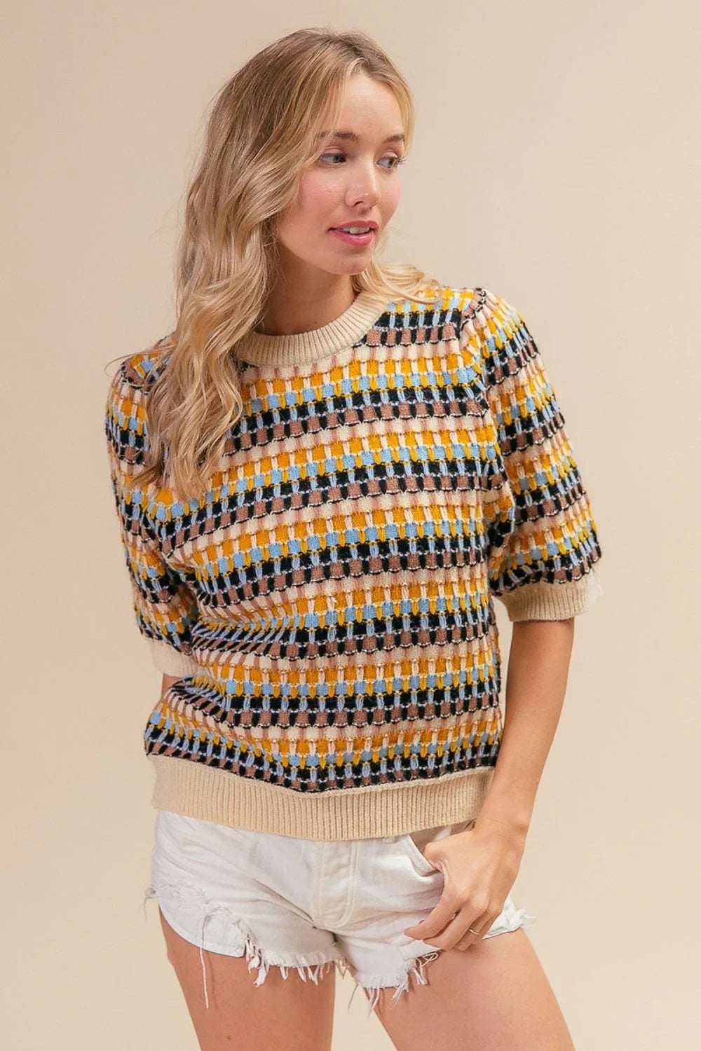 Woman wearing a textured multicolor knit sweater with short sleeves and white denim shorts