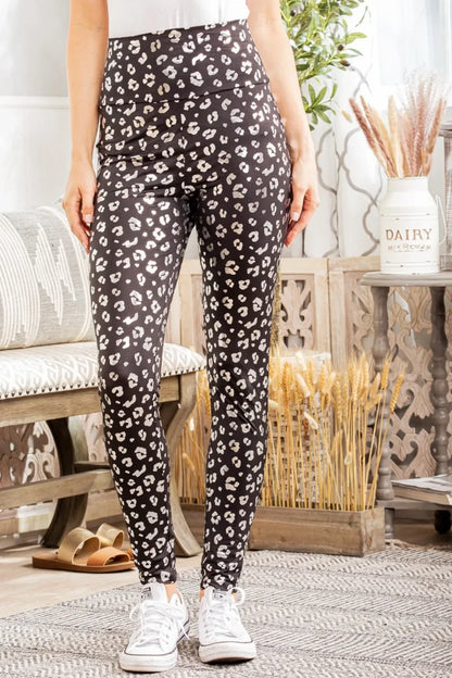 Woman wearing high-waisted black leopard print leggings and white sneakers indoors