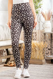 Woman wearing high-waisted black leopard print leggings and white sneakers indoors