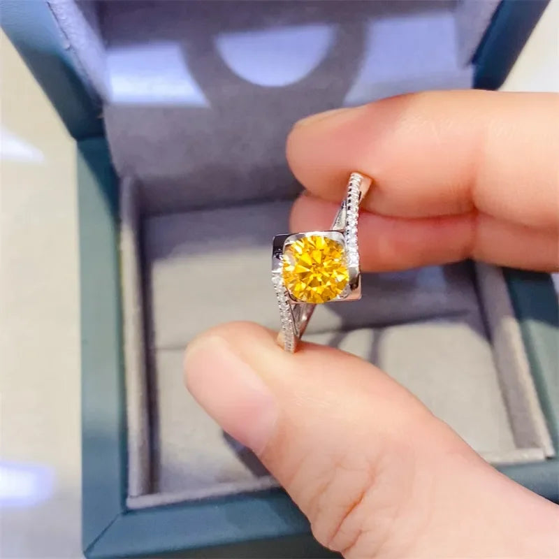 Hand holding a silver ring with a round yellow gemstone, accented by small clear stones