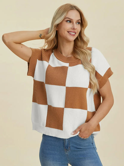 Woman wearing a short sleeve, brown and white checkered knit sweater with blue jeans