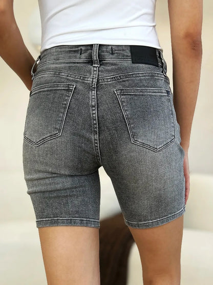 Back view of high-waisted grey denim shorts with pockets, worn with a white top