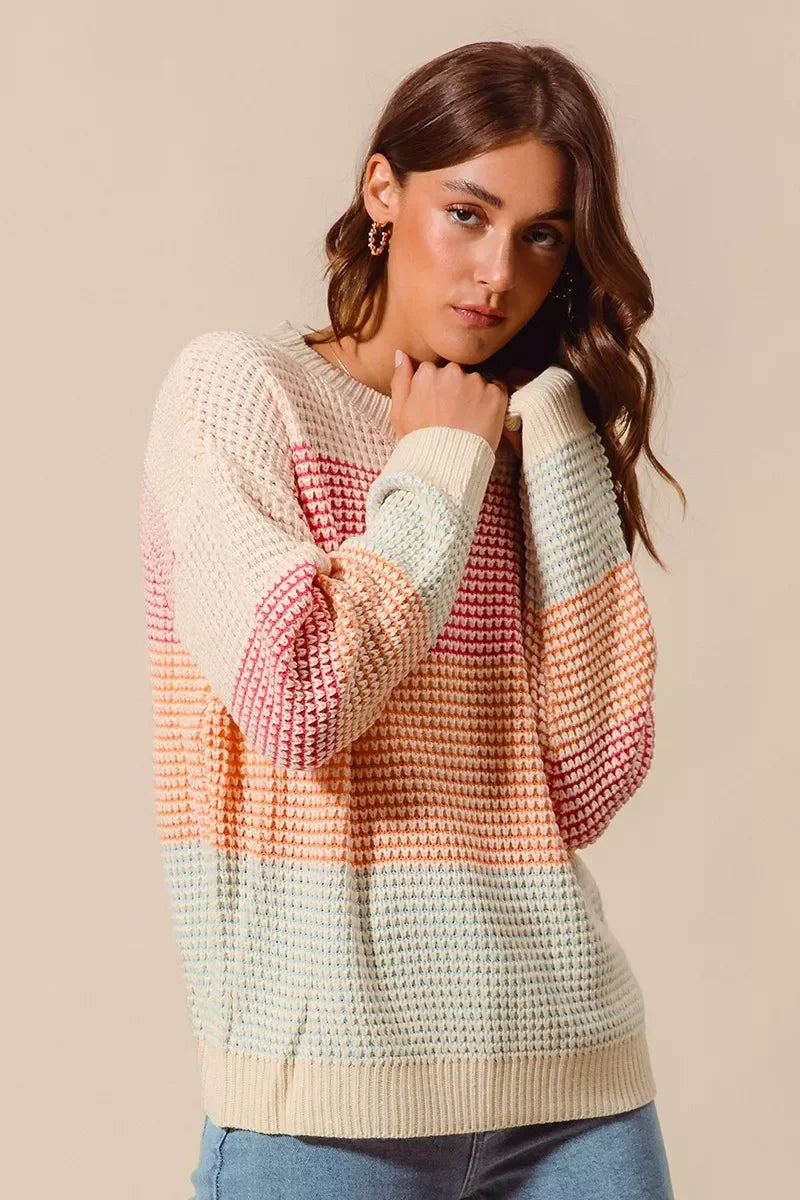 Woman wearing a pastel striped knit sweater with relaxed fit and light wash jeans