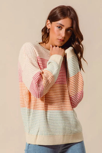 Woman wearing a pastel striped knit sweater with relaxed fit and light wash jeans