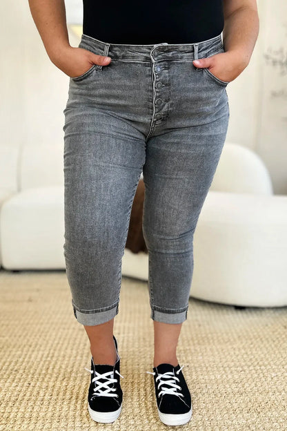 Woman wearing high-rise grey cropped jeans with button fly and black sneakers