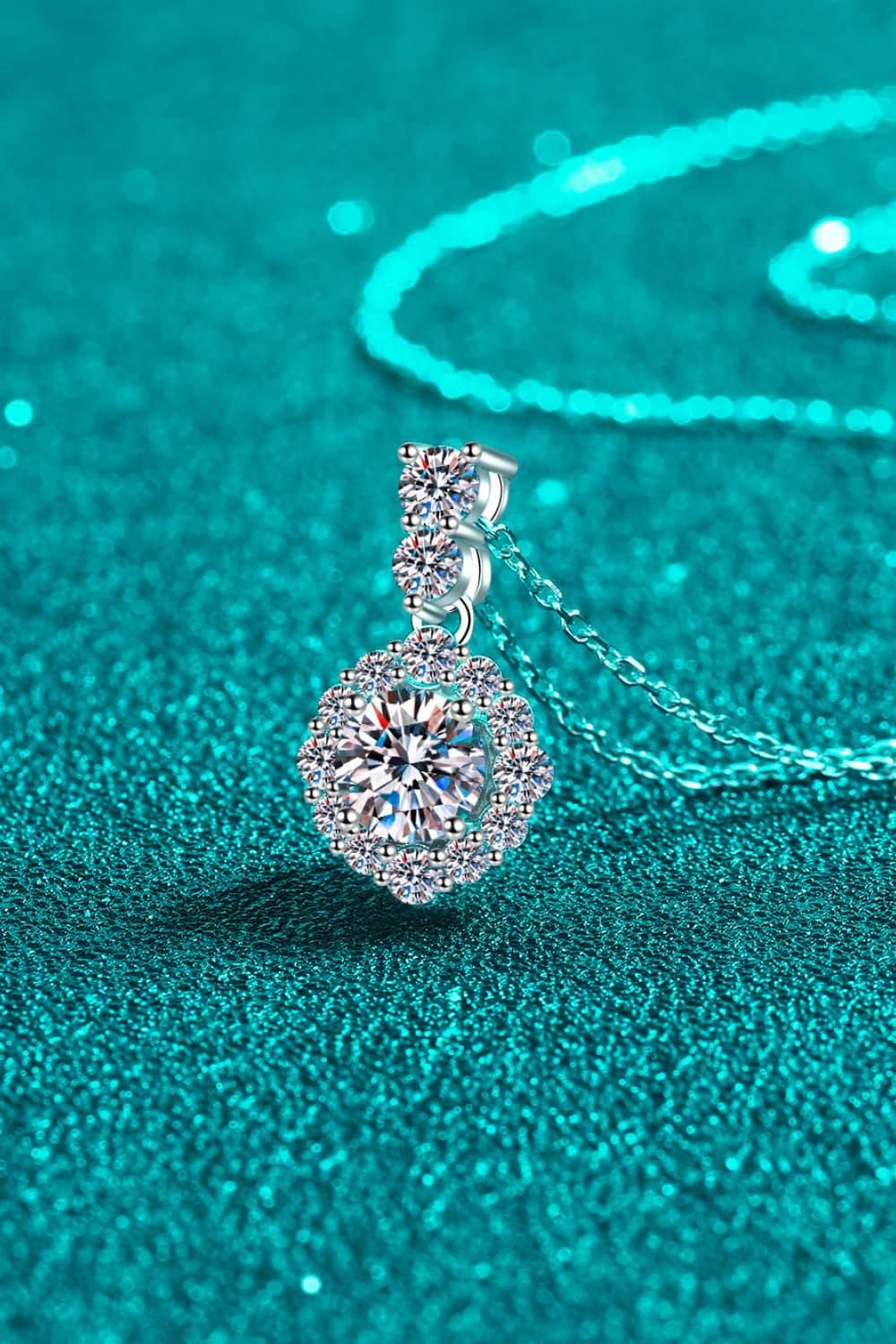 Elegant silver pendant necklace with round crystal gemstones on a shimmering teal background