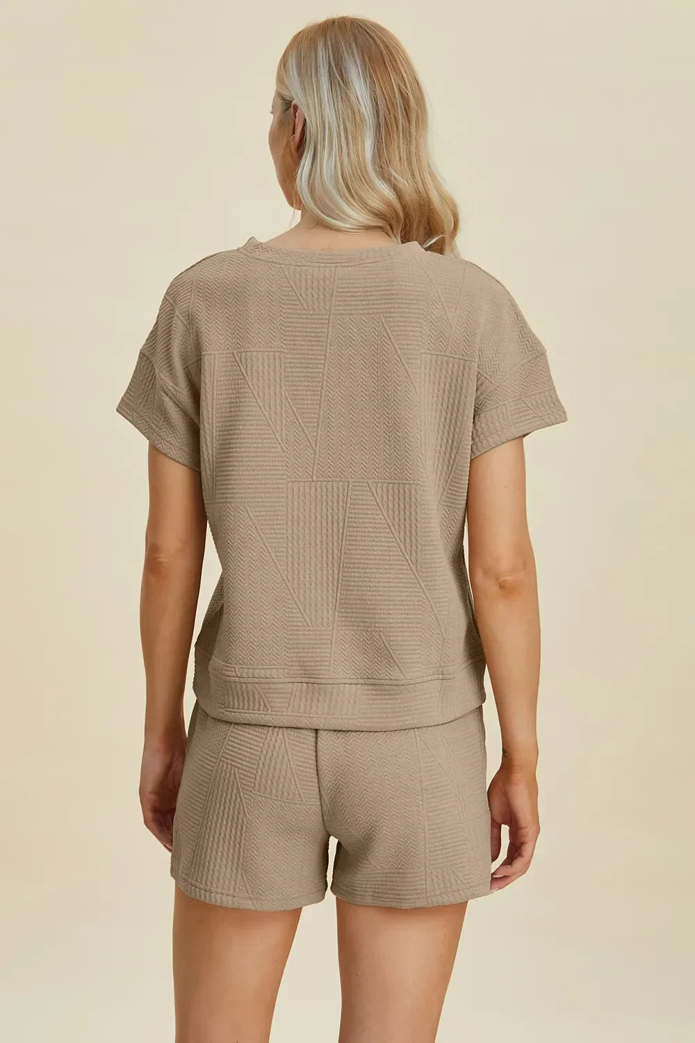 Woman wearing taupe textured short-sleeve lounge set with geometric knit pattern, back view