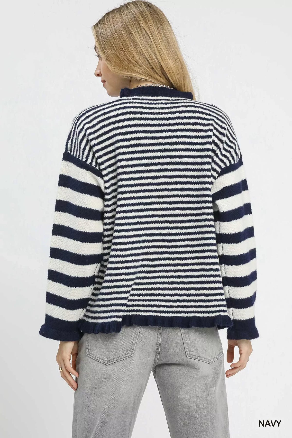 Woman wearing a navy and white striped knit sweater with grey jeans, back view