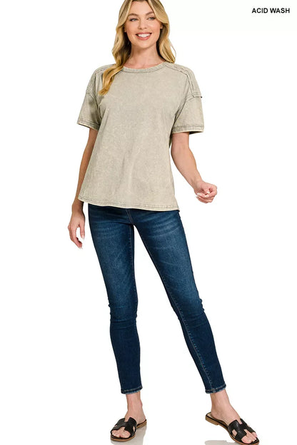 Woman wearing beige acid wash t-shirt, dark skinny jeans, and black sandals standing and smiling.