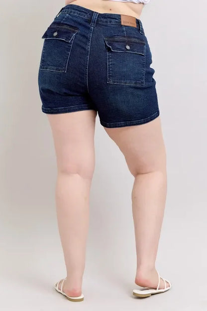 Back view of woman wearing dark denim shorts with flap pockets and white sandals