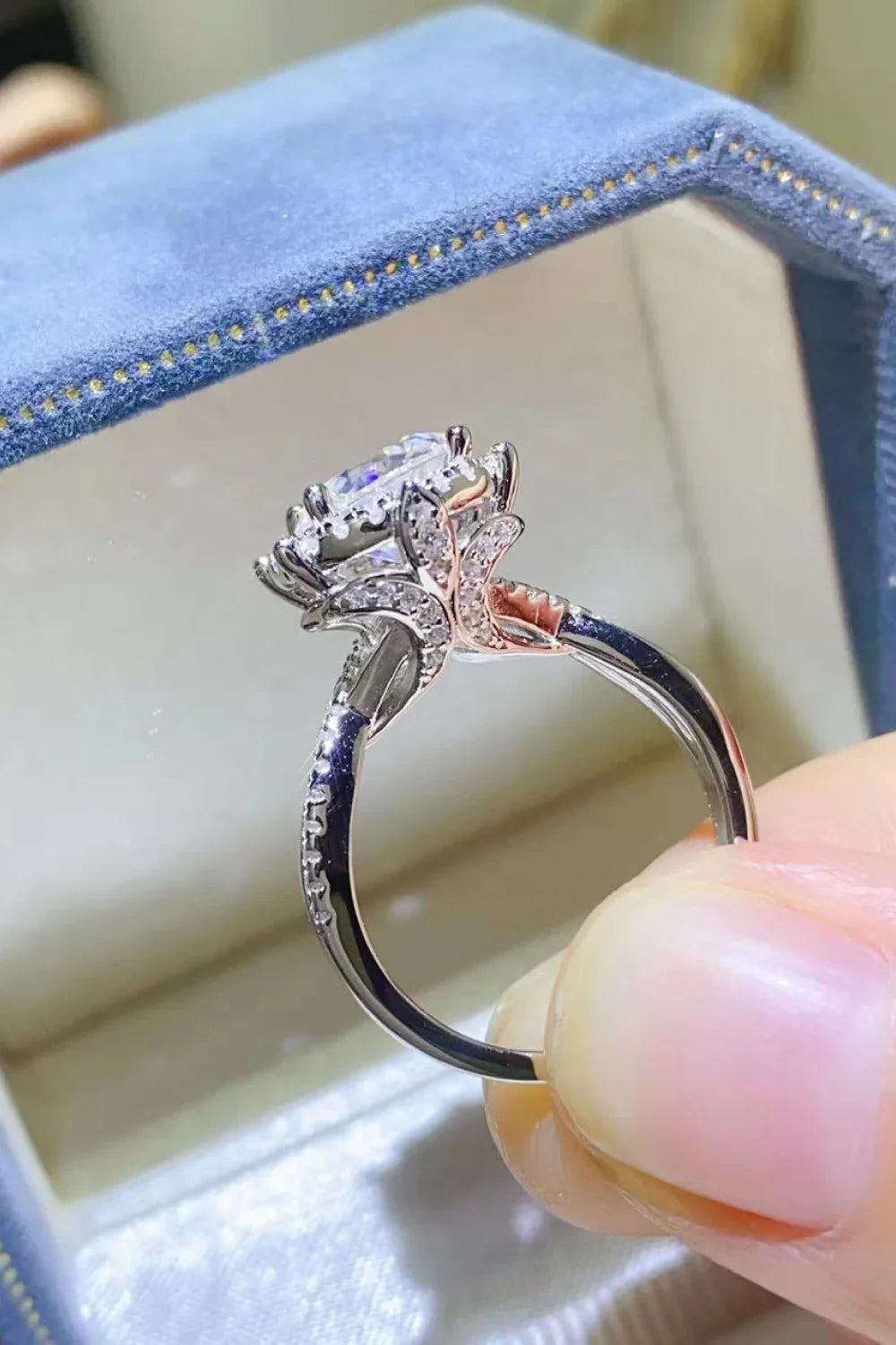 Elegant silver gemstone ring with leaf detailing, displayed in a blue velvet jewelry box