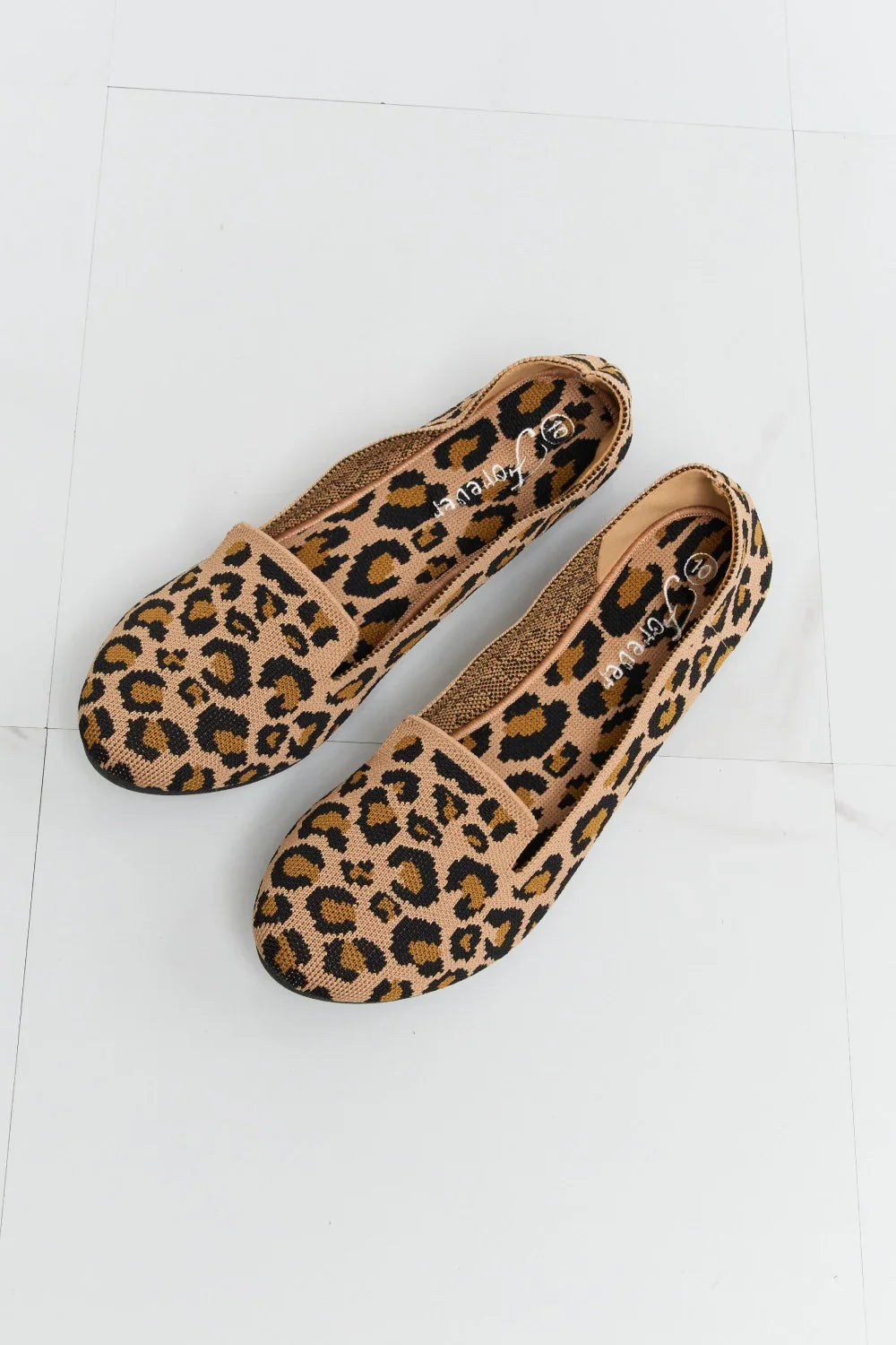 Leopard print women’s flats with round toe on a light tile background, casual slip-on style
