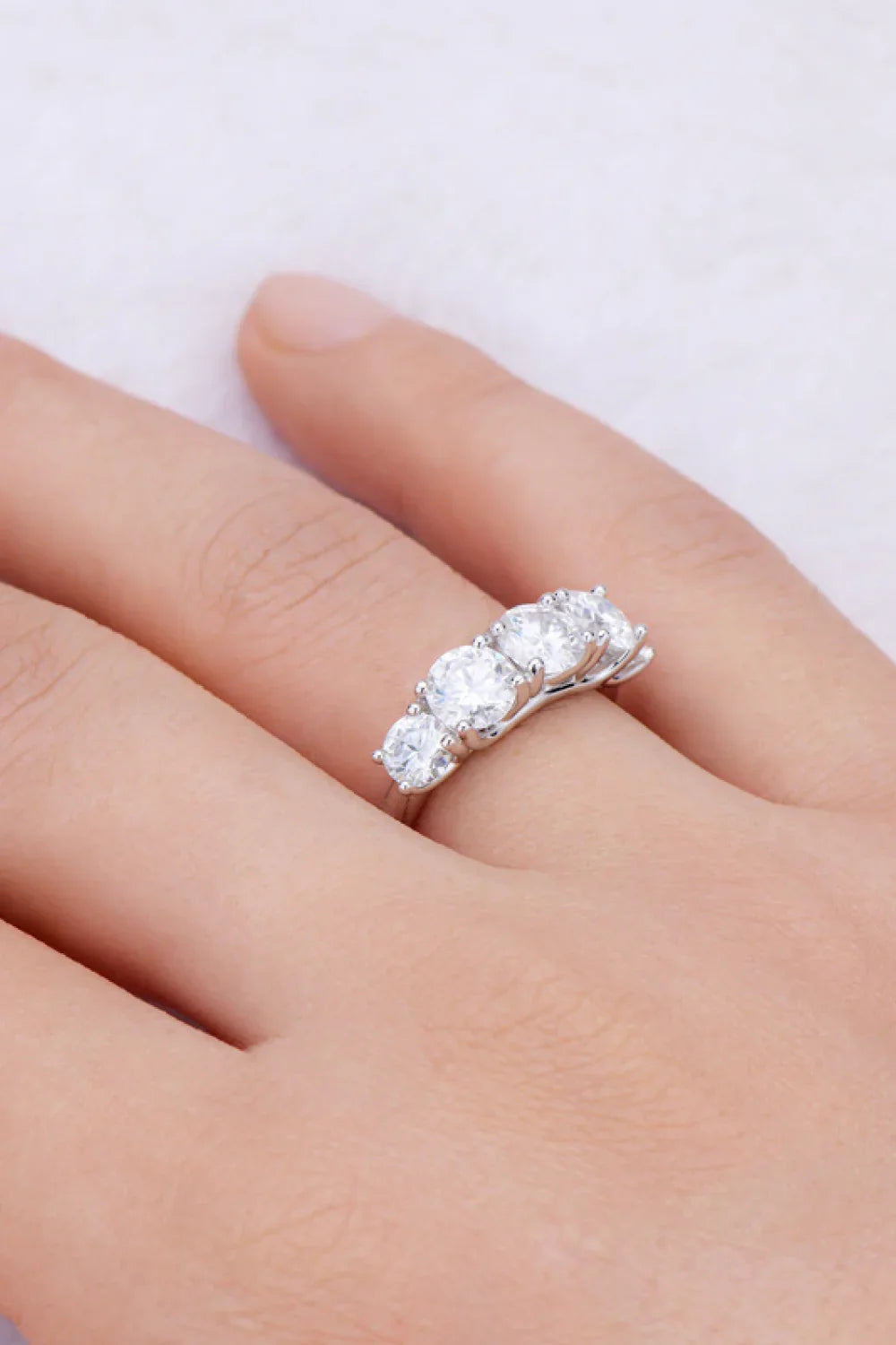Three-stone silver ring with round clear gemstones on a hand, elegant minimalist jewelry