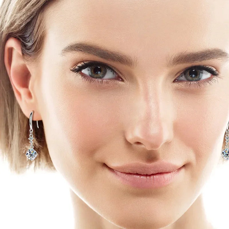 Close-up of woman wearing silver drop earrings with clear gemstone, natural makeup, short hair