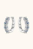 Silver hoop earrings with five round-cut clear gemstones set in a row on a neutral background.