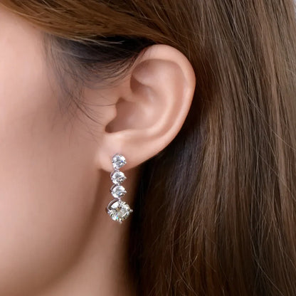Woman wearing a linear drop earring with four round clear gemstones