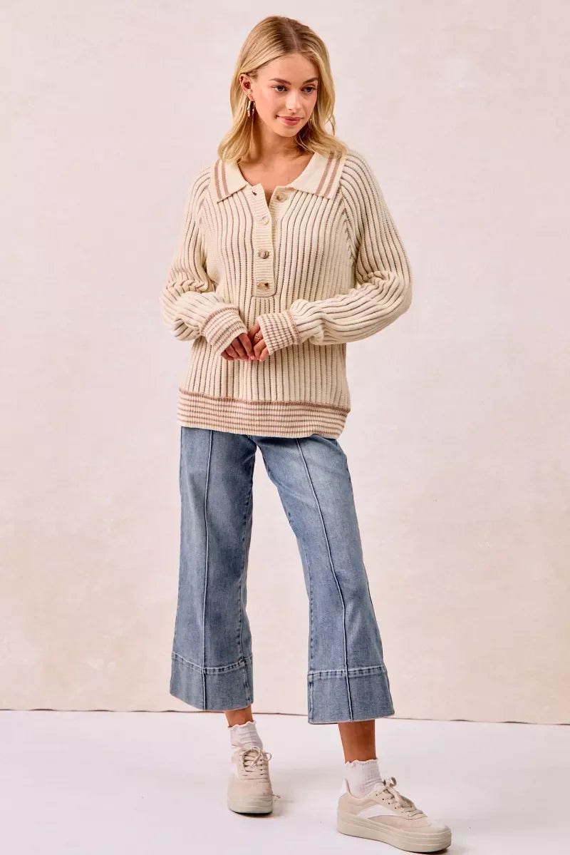 Woman wearing a cream ribbed knit sweater with button-up collar and wide-leg cropped jeans.