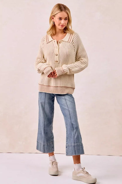 Woman wearing a cream ribbed knit sweater with button-up collar and wide-leg cropped jeans.