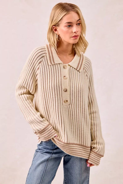 Woman wearing a ribbed cream knit sweater with a collared neckline and button detail, styled with jeans.