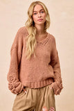 Woman wearing a chunky knit sweater with crochet cuffs and relaxed fit pants in neutral tones
