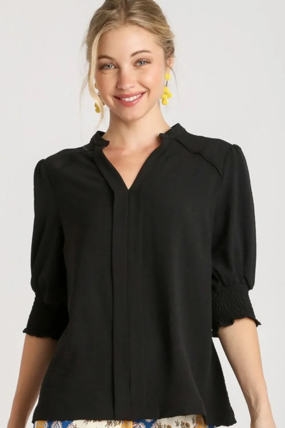 Woman wearing black V-neck blouse with puff sleeves and smocked cuffs