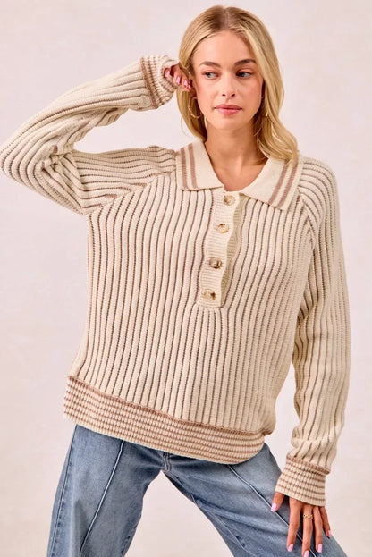 Woman wearing a cream ribbed knit sweater with buttons and collar, paired with blue jeans