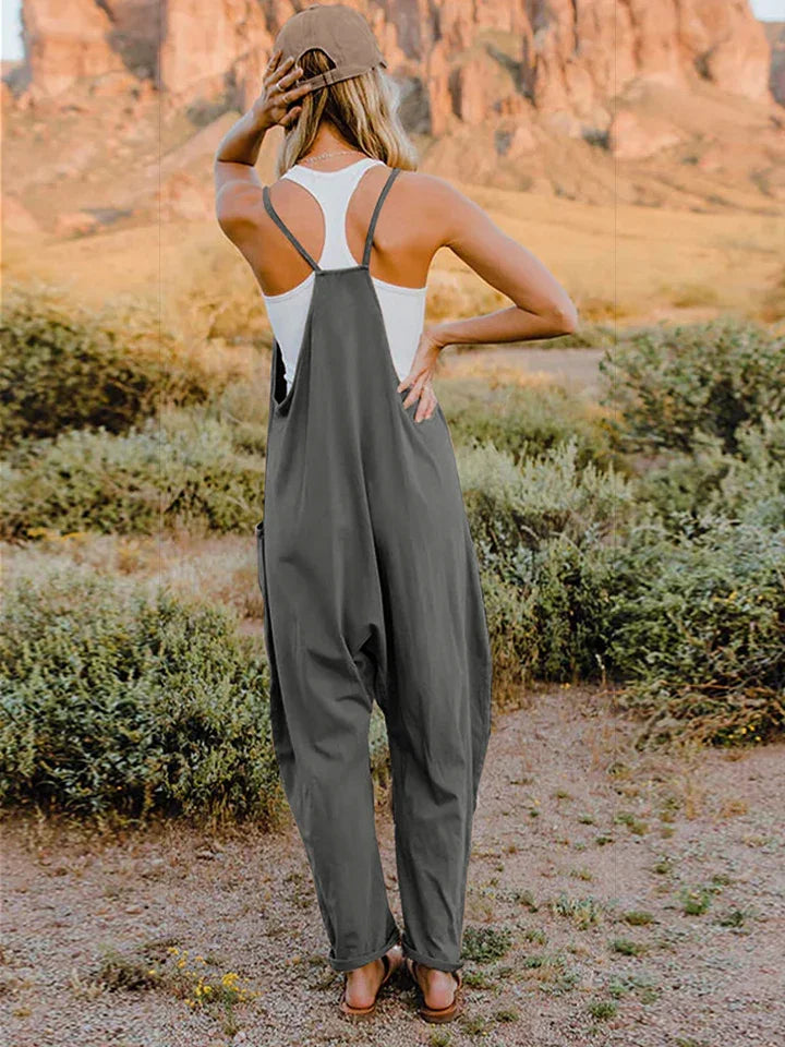 Woman wearing relaxed grey overalls and a white tank top outdoors in a desert landscape